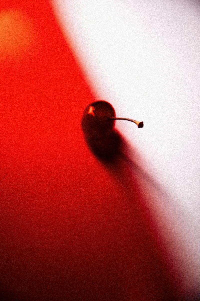 Cherry on white background half obscured by red filter