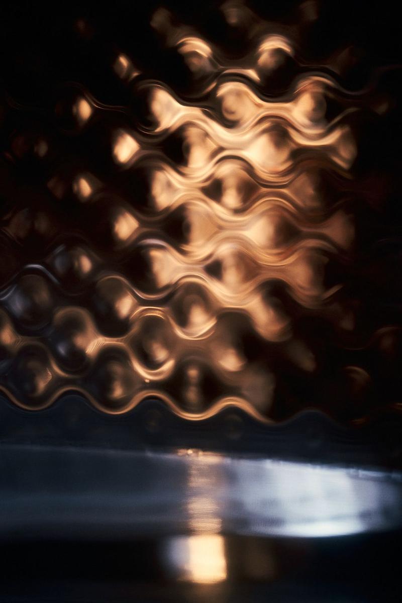 Golden distorted reflections in stainless steel wine vat