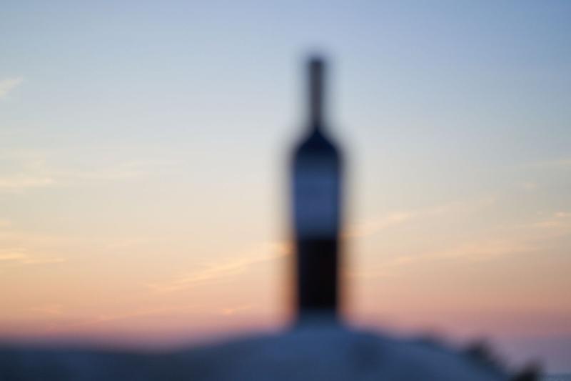Out of focus bottle of chateau Clinet sat on rock against sunset sky