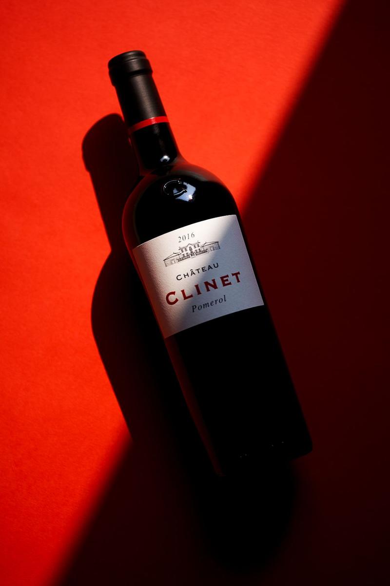 Bottle of chateau clinet against red background, half in shadow