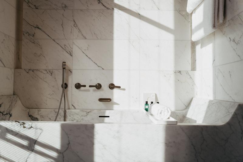 Sun casting light and shadows across a marble bathtub at Hotel Lutetia