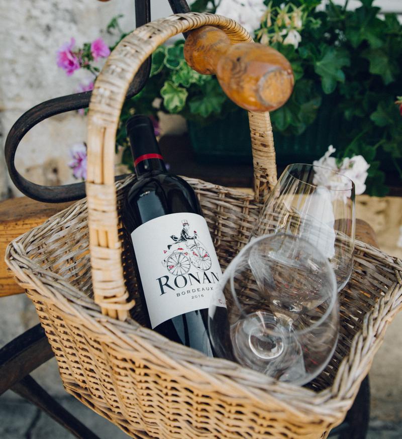 Bottle of Ronan by Clinet wine sitting in picnic basket with wine glasses